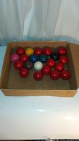 Box with 21 billiard balls arranged, showing multiple red balls and a range of colored balls including white.