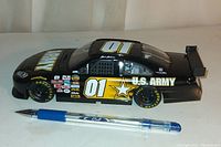 Side profile of black die cast U.S. Army race car with number 01, 8 inch length shown next to pen for scale