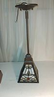 Full view of the lamp showing the hanging style metal fixture with attached stained glass pyramidal shade.