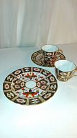 View of one cup, one saucer, and one lunch plate showing the Imari floral and geometric gold-accented decoration.