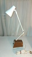 Full view of desk lamp showing white adjustable arm and shade, brown base, power cord and plug.