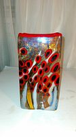 Front view showing vibrant colorful pattern with red black circles and shiny gold iridescent background on rectangular vase with red rim.