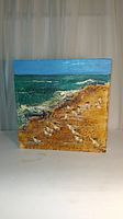 Front view of textured painting showing ocean, sandy beach and seagulls.