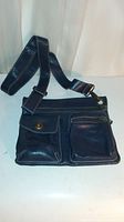 Front view of navy blue leather messenger bag showing pockets and adjustable strap