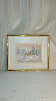 Full view of the framed painting showing the cabin in winter landscape with snow, pine trees and pastel sunset sky.