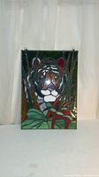 Front view of rectangular stained glass panel depicting a tiger in foliage with hanging loops on top.