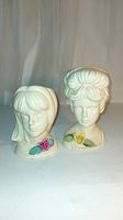 Front view of two vintage ceramic head vases with floral decorations and detailed hairstyles.