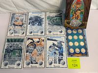 Full view of six illustrated booklets and coin display board with ten coins arranged in blue card holder and colorful box to the side.