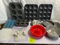 Overview of the bakeware lot showing muffin tins, cake pans, bundt cake silicone mold, angel food cake pan, circular cake insert, lattice cutter, and assorted cookie tools.