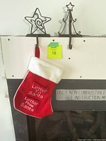 Two wrought iron stocking holders, one star-shaped and one Christmas tree-shaped, each holding a red and white stocking with text 'Letter to Santa'.