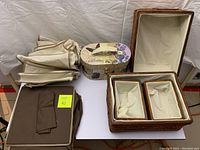 Four closet organization items displayed together: brown fabric hanging sweater/shirt organizer folded, Paris themed jewelry box with mirror, set of four wicker baskets with fabric liners, and fabric shoe organizer folded.