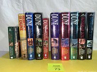Front view of all 11 Dune series paperback books arranged standing in row showing titles and authors.