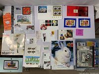 Overview of lot showing assortment of first day covers, year of the rabbit cover, NHL All-Stars collector packs, and assorted uncirculated stamps in sleeves and blocks.