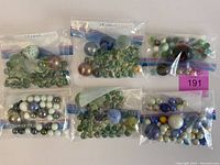 Overview of six plastic bags each filled with various marbles of assorted colors and sizes including large marbles