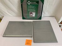 Three metal mesh bulletin boards on white surface, one still in packaging, two out of box showing size difference and condition.
