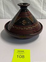Photo of the full Moroccan ceramic tajine with decorative conical lid and round base, placed on white backdrop with auction tag visible in front.