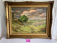 Front view of the framed oil painting showing the rural farmyard scene, ornate gold frame, and signature.