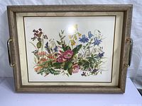 Floral tea tray with wood grain border and golden handles showing botanical flower print.