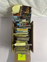 Top view of postcards sorted in a cardboard box with sticky notes labeling some countries like Ireland and Yugoslavia