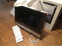 Front view of shrink-wrapped iMac with keyboard, cable and box