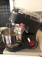 Front and side view of black Bodum tilt-head stand mixer with stainless steel bowl on counter, showing power cord and controls.