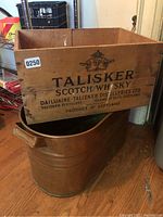 Photo of wooden whiskey box branded Talisker Scotch Whisky placed on top of the copper boiler showing front logo and markings.