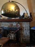 Full view of lamp showing brass shade, curved black arm, and black marble base in living room setting