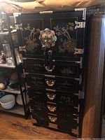 Front and right side view of the tall black lacquer cabinet with decorative motifs.