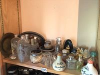 Wide view of the entire collection on a wooden shelf showing various sizes and styles of perfume and apothecary bottles.