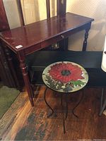 Set showing the wooden console table with drawer and turned legs, black low shelf table behind, and round floral patterned table in front.
