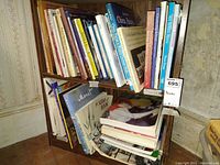 Wide shot of wooden shelf with multiple books on art, dolls, sewing and others, some stacked horizontally