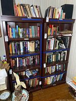 Full view of two dark wooden bookshelves filled with books showing size and condition.