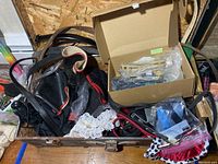 Open trunk showing belts, vintage accessories, and men's ties inside along with a box of small items