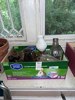 Top view of box containing vintage oil lamps and glass shades on a windowsill.