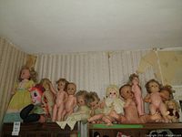 Shelf with vintage plastic baby dolls with varying hair styles and skin tones, mostly undressed