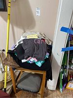 Pile of women's clothing on a chair, various items mostly casual wear size small to medium