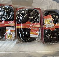 Photo of three sealed packs of Max brand human hair wigs in curly style and varying dark to burgundy colors.