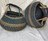Two hand woven Bolga baskets placed side by side, showing the front and bottom of one basket.