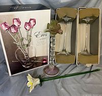 Photo showing two boxed Orrefors crystal candle holders, Eros Rose Bouquet box with six glass roses and glass vase, and two individual handmade glass flowers.