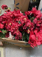 Box filled with new silk poinsettia bouquets featuring rich red flowers and green leaves.