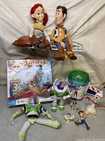 Full assortment of Toy Story toys on white surface, showing plush dolls, figures, and boxed Buckaroo toy.