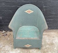 Front view of green wicker child's wing back chair showing decorative diamond pattern on backrest and seat area.