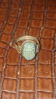 Front view of ring showing turquoise scarab bezel and braided band