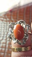 Ring worn on finger showing full front view of oval coral and diamond filigree petals