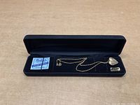 Gold filled heart-shaped locket necklace displayed in a black velvet box with chain neatly placed inside.