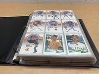 Open binder showing 9 Fleer 1990 baseball cards in sleeves featuring players in action with colorful rainbow stripe design