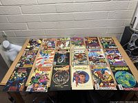 Top view of 21 assorted comic books spread out on a table, showing Marvel and DC superhero titles