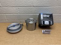 Full view of all items in the Stanley camping cook set including the pot, pan, clear lid, insulated carrying case, and original box.