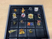 Full set of 15 collector sports pins arranged in a black tray showing mostly NFL team and Super Bowl themed pins.