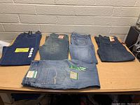 Overview of five pairs of women's jeans including various blue denim styles laid out on table